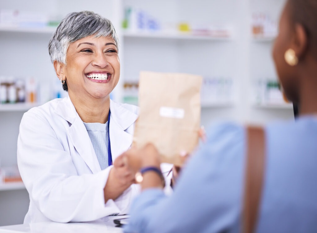 Pharmacist handing a prescription bag to a patient over the pharmacy counter